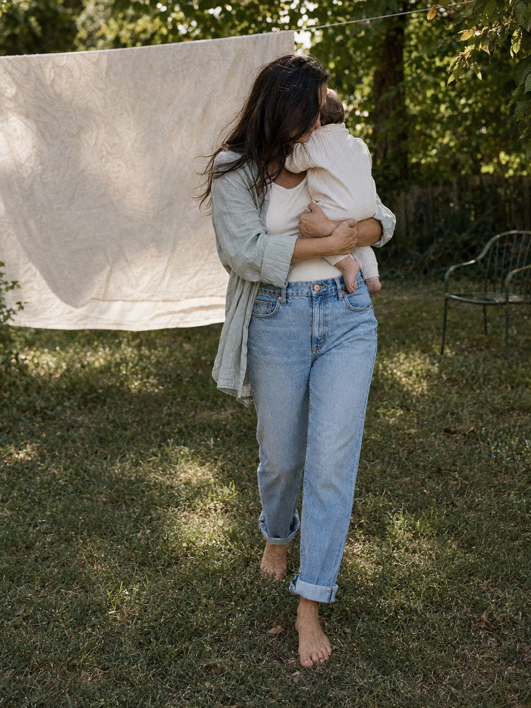 A mother holding her baby while wearing Ginger and Dandelion jeans